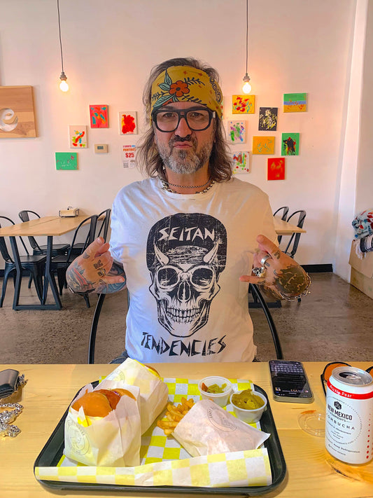 Olivier Fox Renard Founder of White Buffalo Vegan Apparel showcasing his "Seitan Tendencies" t-shirt creation while eating a vegan cheese Burger at Lucky Goose in Albuquerque New Mexico 